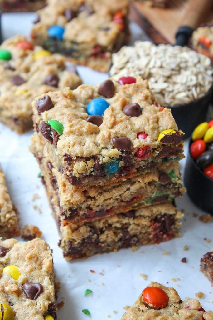 Stacked monster cookie bars highlighting their dense, chewy layers and bright candy pieces