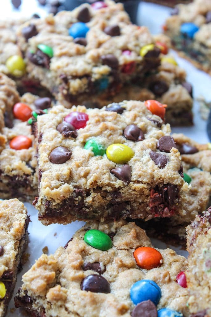 Monster cookie bars on parchment paper with a thick, soft texture and crunchy edges