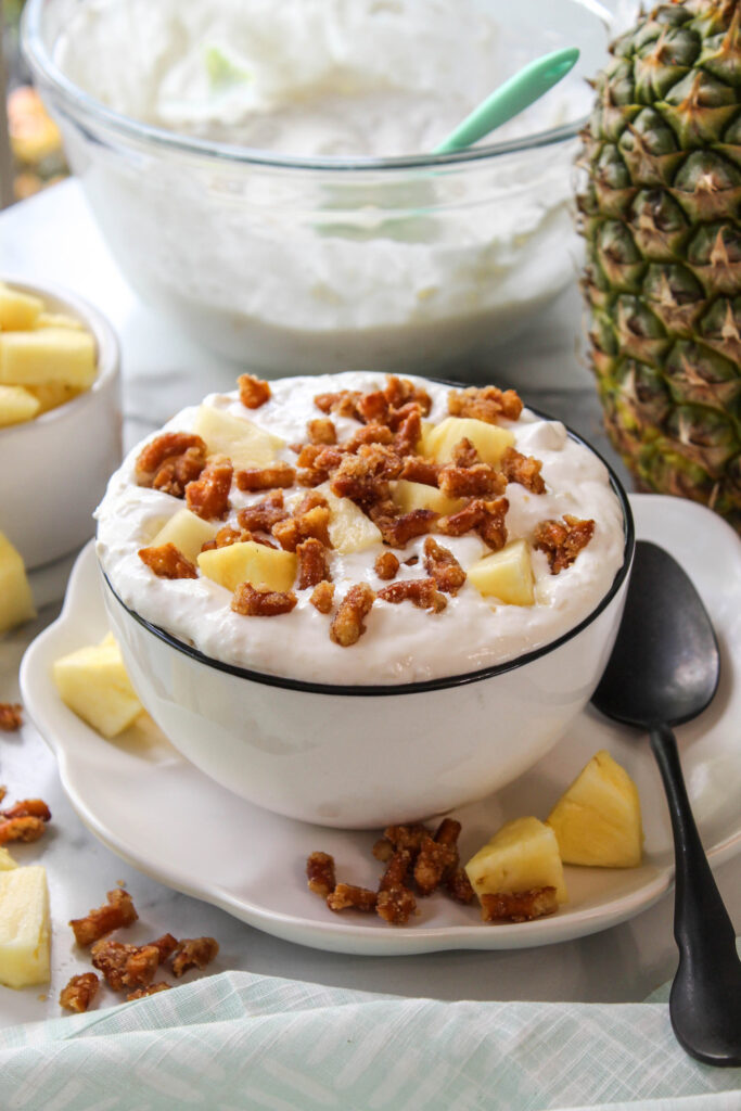 Sweet and salty pineapple pretzel salad fluff topped with extra pretzel crumbles in a glass serving dish
