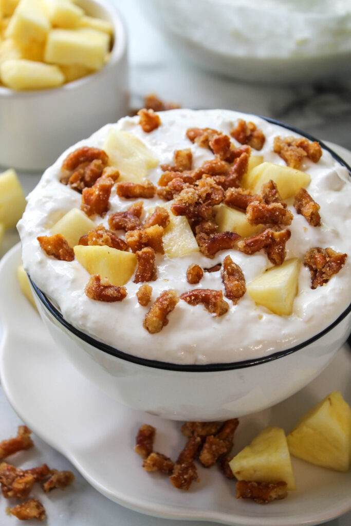 Light and fluffy pineapple dessert with whipped topping, pineapple chunks, and crunchy pretzel pieces mixed throughout