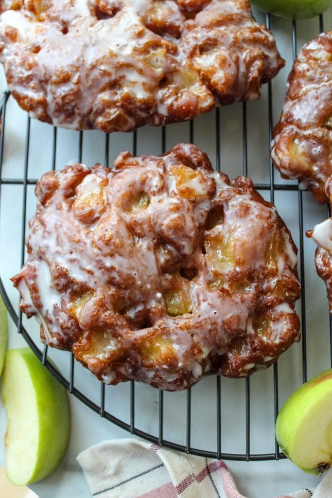 Homemade apple fritters filled with diced apples and coated in icing