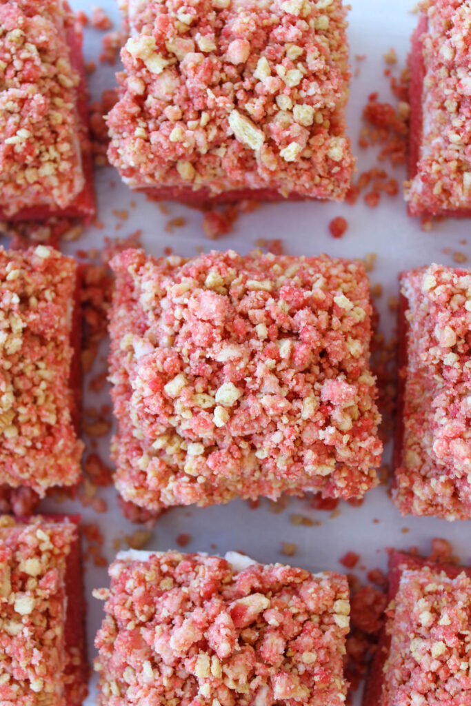 Sliced strawberry crunch cheesecake brownies stacked on a plate