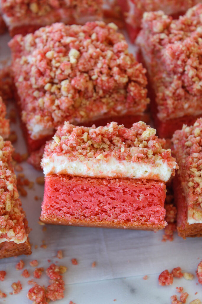 Close‑up of strawberry crunch cheesecake brownies showing creamy cheesecake and crumbly strawberry crunch layer