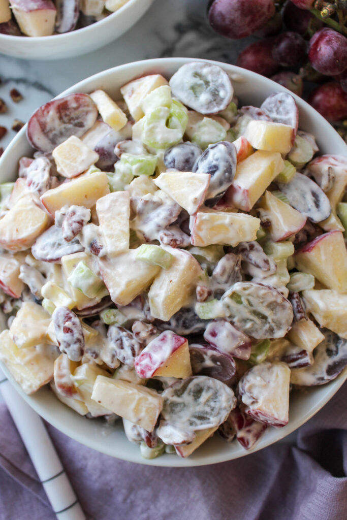Fresh Waldorf salad featuring diced apples, halved grapes, celery, and nuts
