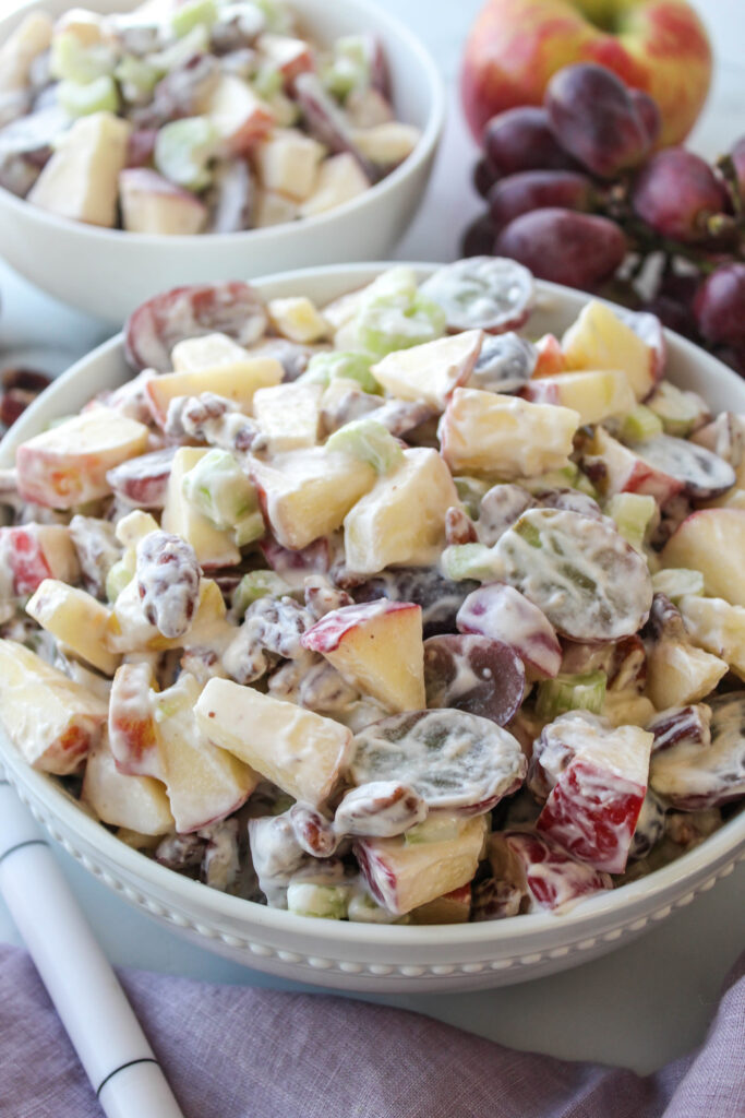 Waldorf salad served in a bowl with apples, grapes, celery, and whipped dressing