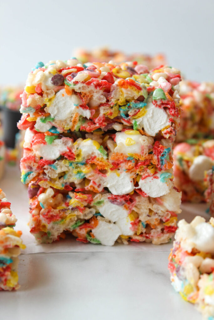 Fruity Pebbles Rice Krispie treats stacked with colorful cereal and gooey marshmallows
