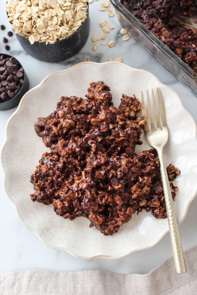Brownie baked oatmeal with a soft, fudgy texture and melted chocolate chips on top, served on a plate