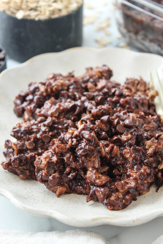 A warm plate of brownie baked oatmeal with a rich, chocolatey crumb and gooey chocolate chips, slightly crisp on the edges and soft in the center
