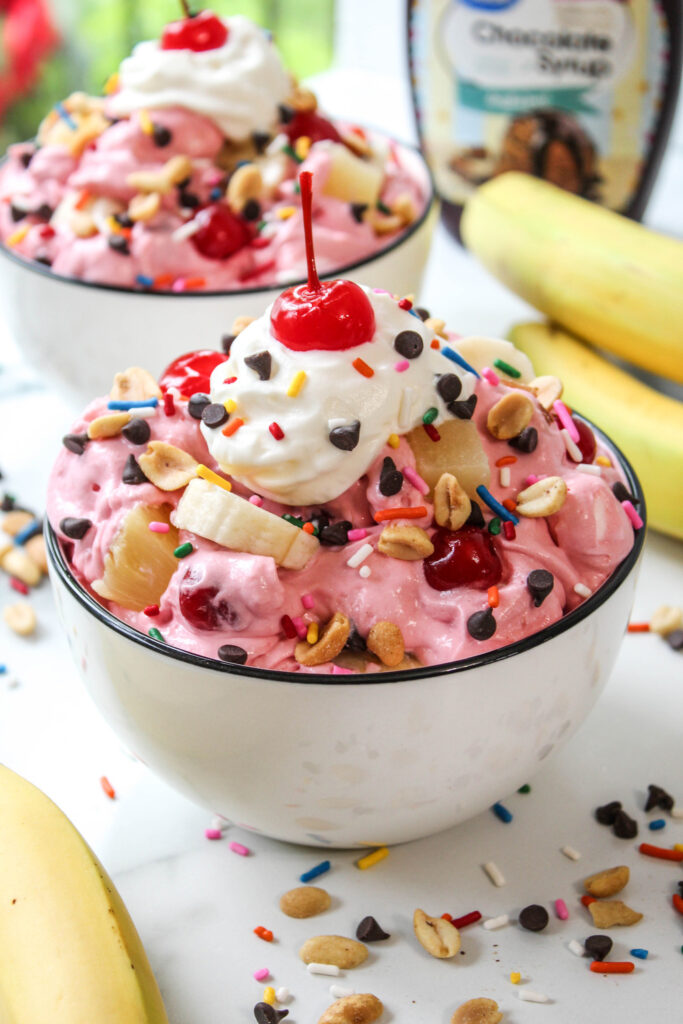 Creamy banana split fluff with whipped topping, bananas, pineapple, cherries, and marshmallows