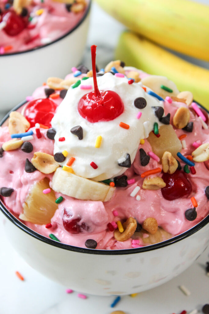 Bowl of banana split fluff made with sliced bananas, crushed pineapple, cherries, mini marshmallows, and whipped topping
