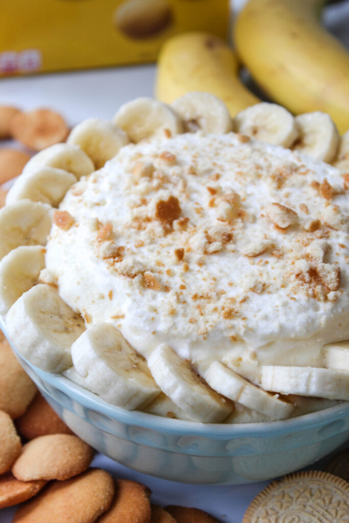 Close-up of creamy banana dip layered with fresh bananas and sprinkled cookie crumbs