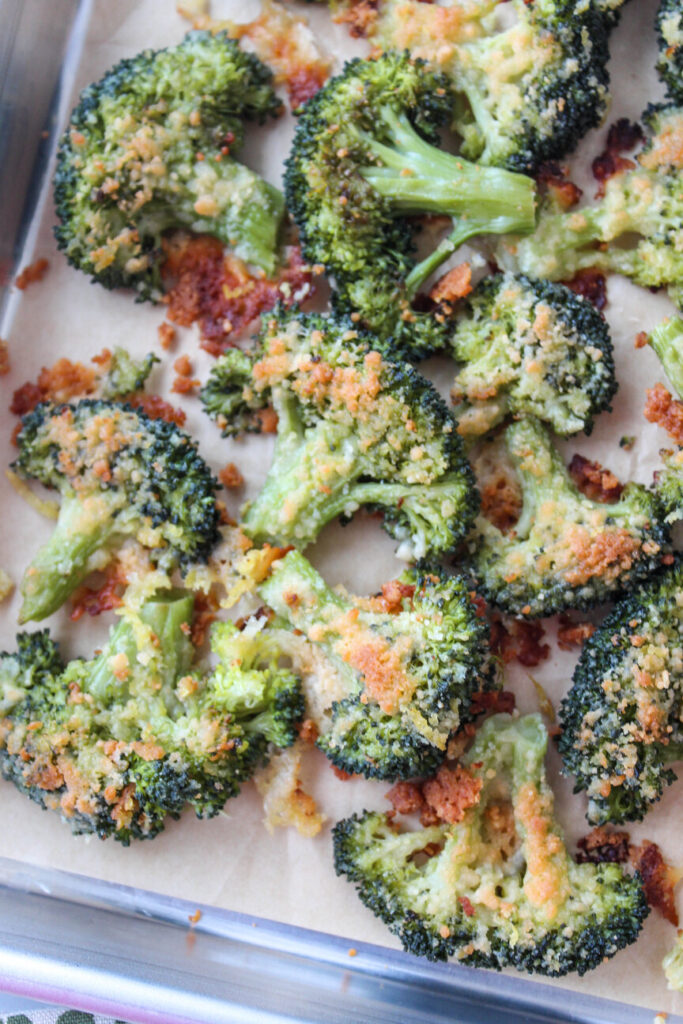 A pan of smashed broccoli topped with grated parmesan cheese
