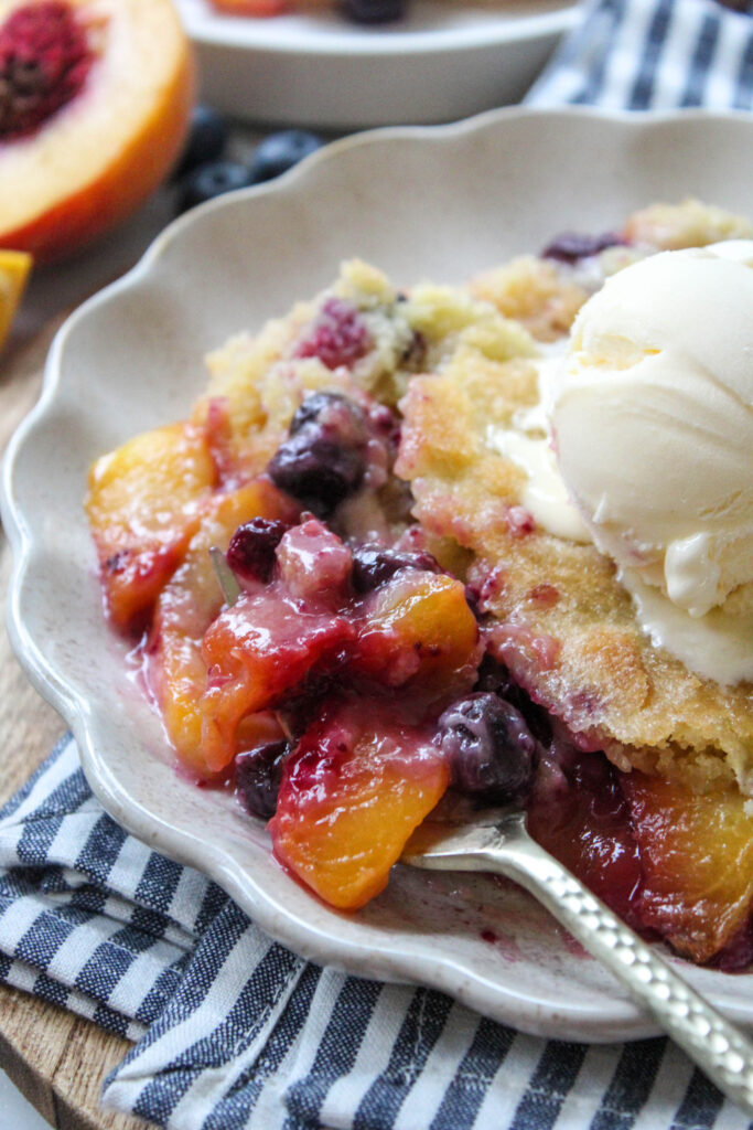 Slice of peach blueberry cobbler showing tender crumb and juicy fruit layers