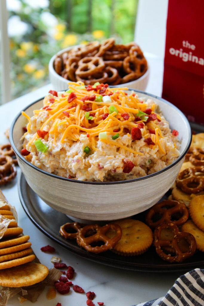 Creamy crack dip topped with bacon, cheddar cheese, and green onions