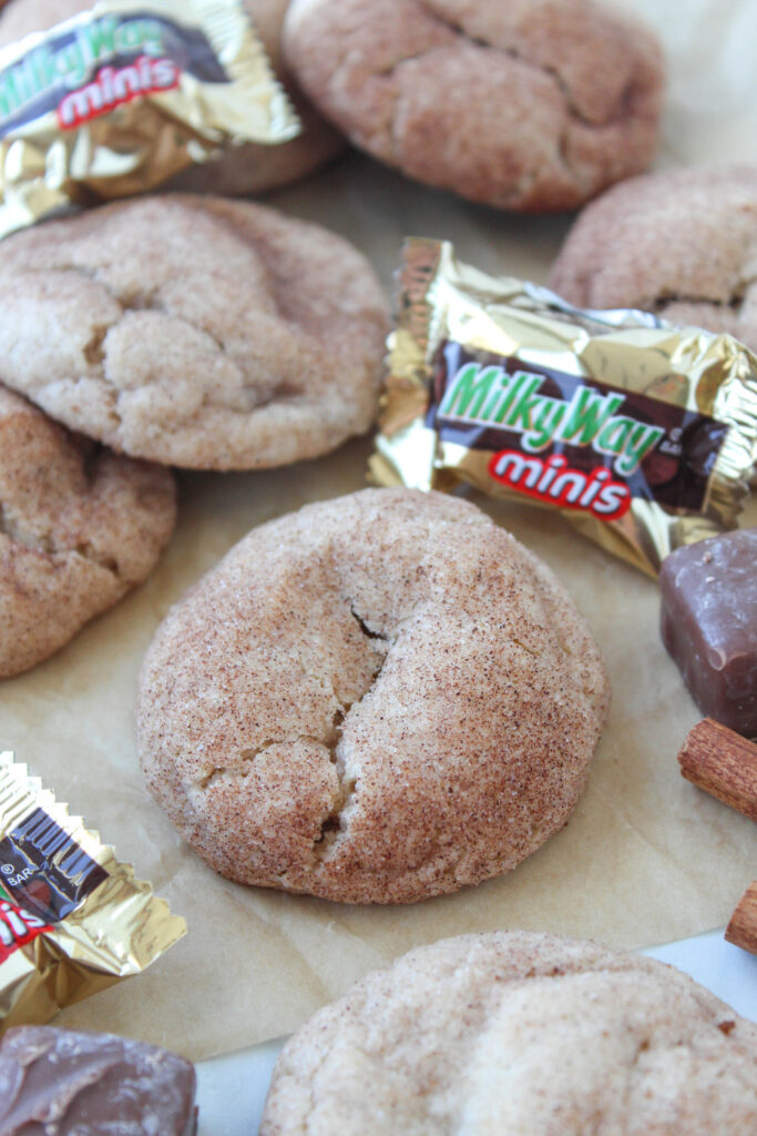 Homemade cinnamon sugar cookies filled with Milky Way candy, featuring a melted chocolate and caramel surprise inside