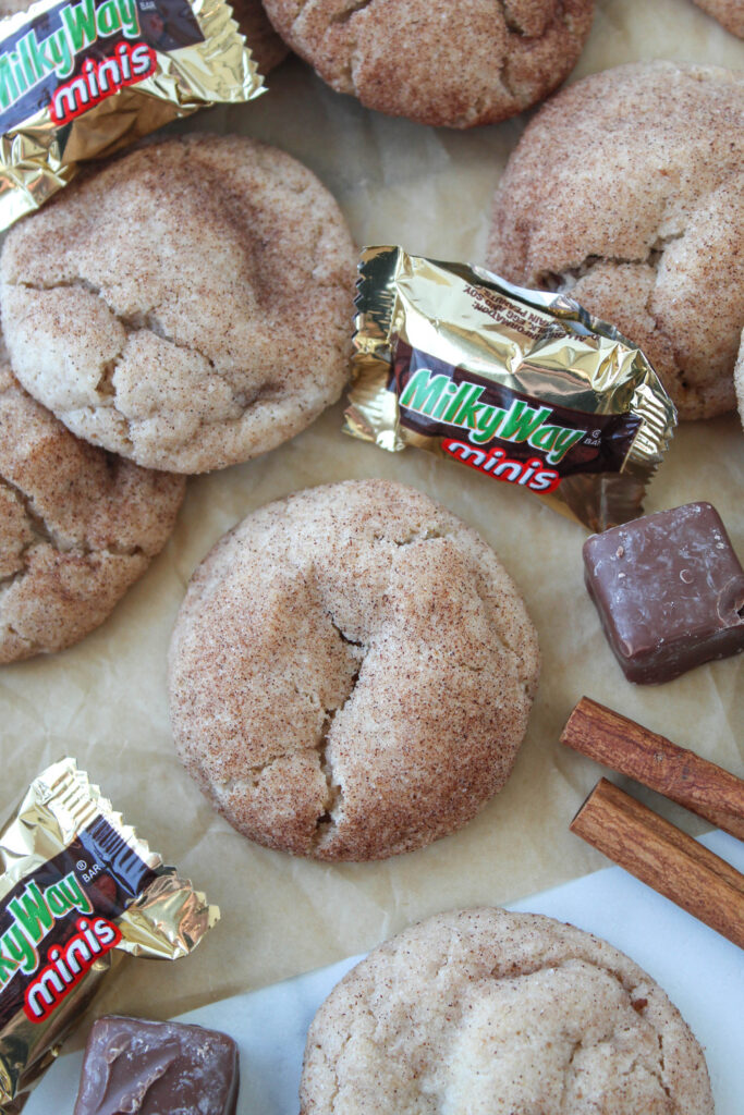 Golden brown snickerdoodles rolled in cinnamon sugar and stuffed with Milky Way chocolate