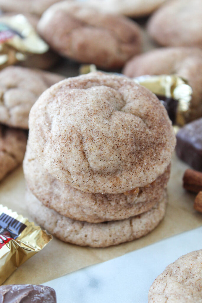 Stack of Milky Way stuffed snickerdoodles with one cookie split open to display the soft caramel and chocolate filling