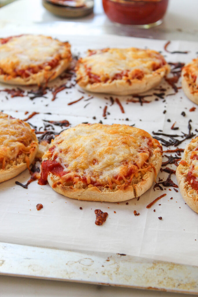 English muffin pizzas topped with melted cheese and pizza sauce