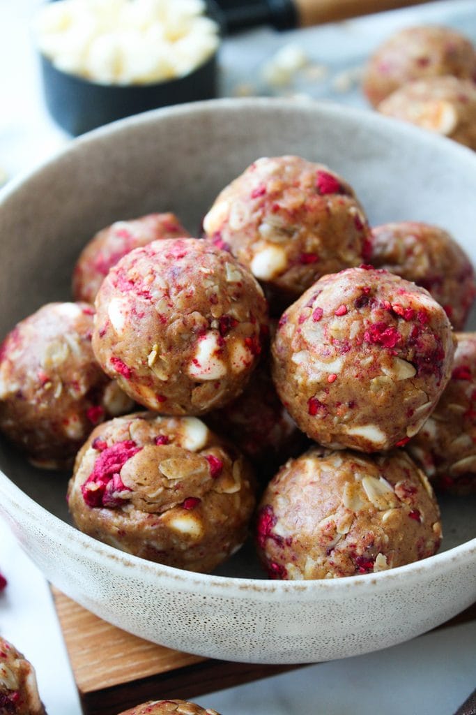 Soft white chocolate raspberry protein balls stacked in a small bowl