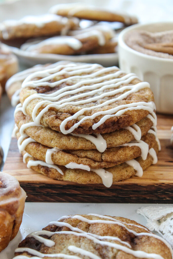 Soft cinnamon roll cookies with visible cinnamon spirals, topped with a rich vanilla glaze