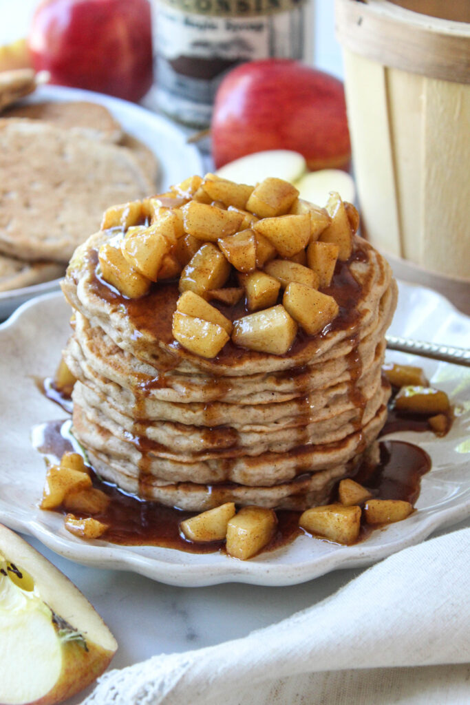Golden brown apple cinnamon pancakes stacked on a breakfast plate