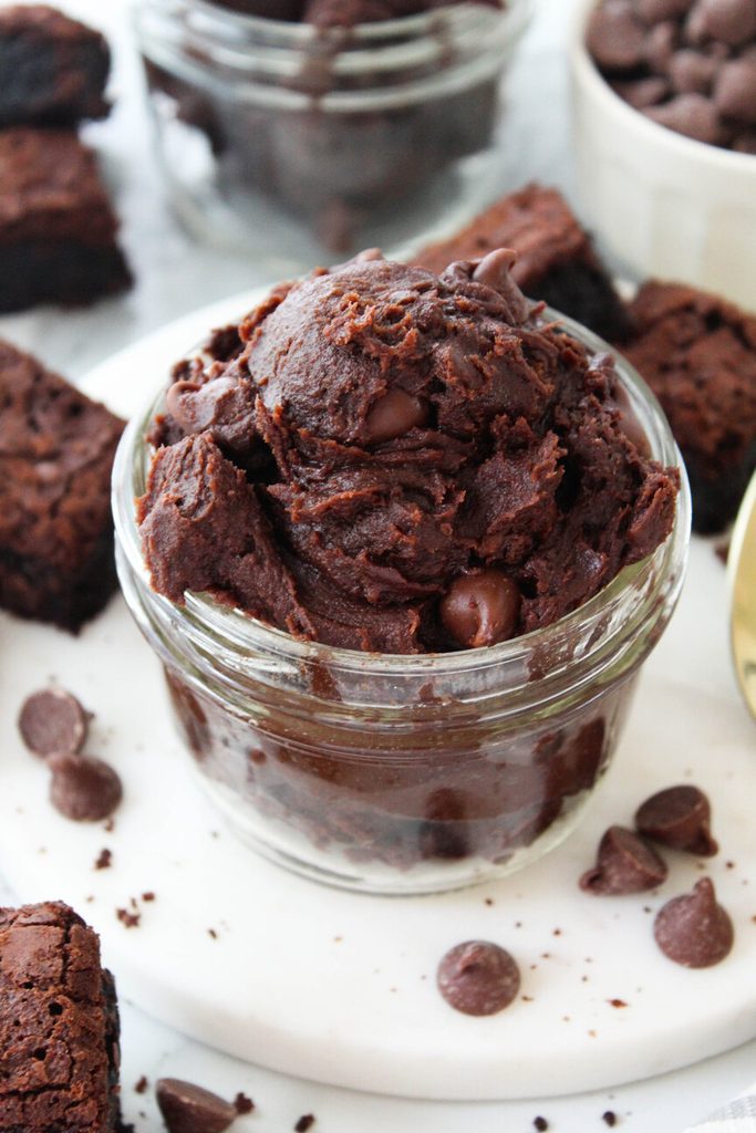Edible brownie batter served in a small bowl with a spoon beside it