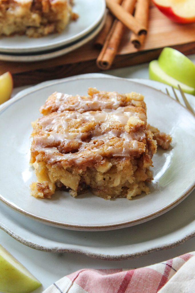 apple fritter cake topped with vanilla glaze on a rustic fall plate

